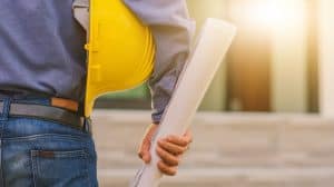 contractor holding blueprints and a hardhat 
